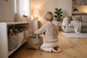 Lapsi laittaa leluauton matalaan avokoriin olohuoneen lattialla
