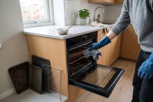 Uunin sisäpinnan pyyhintä mikrokuituliinalla, pellit ja ritilä otettu pois